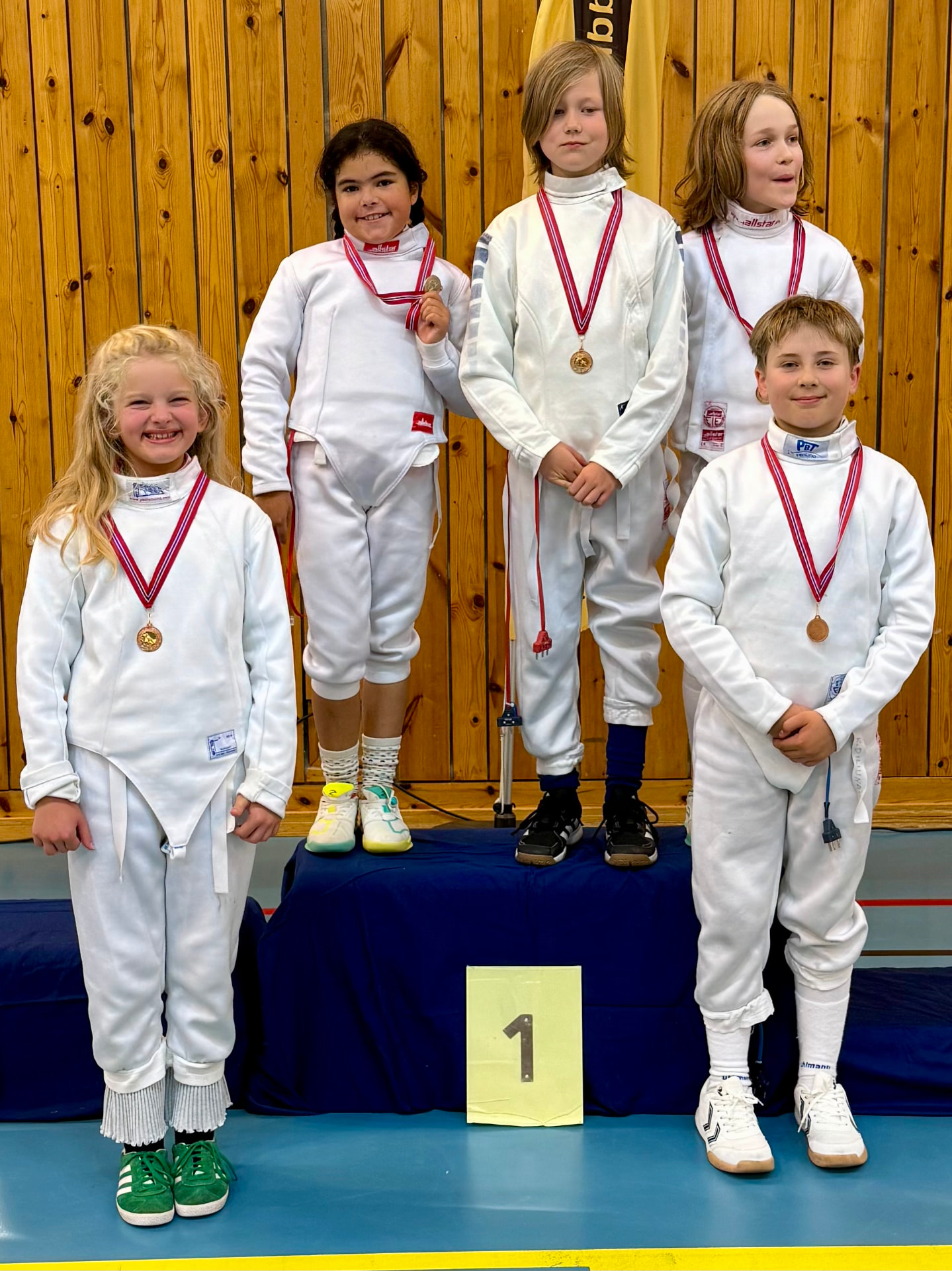 Unge fektere med medaljer på seierspallen etter en konkurranse