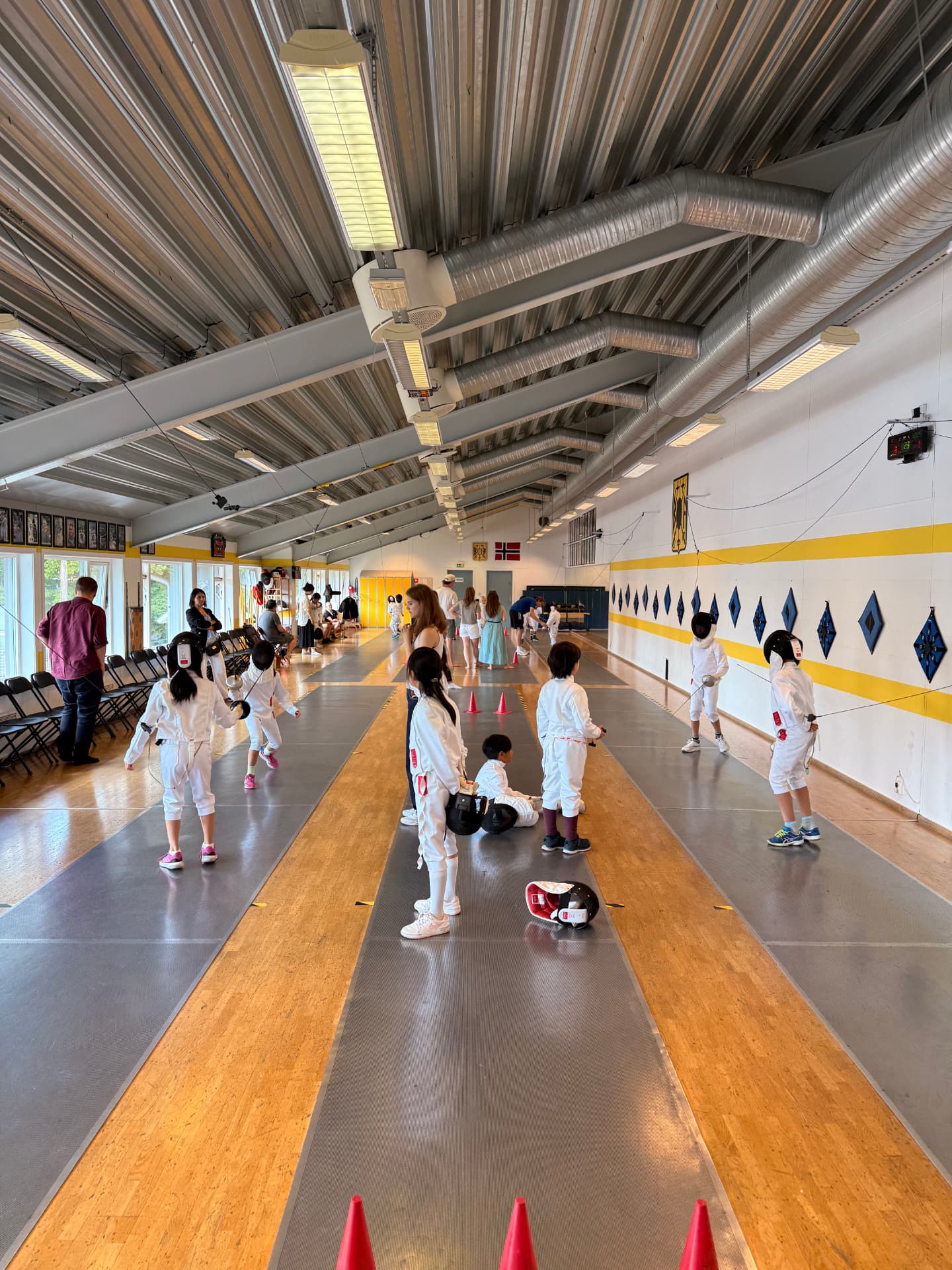 Oversiktsbilde av fektehallen med barn på flere fektebaner