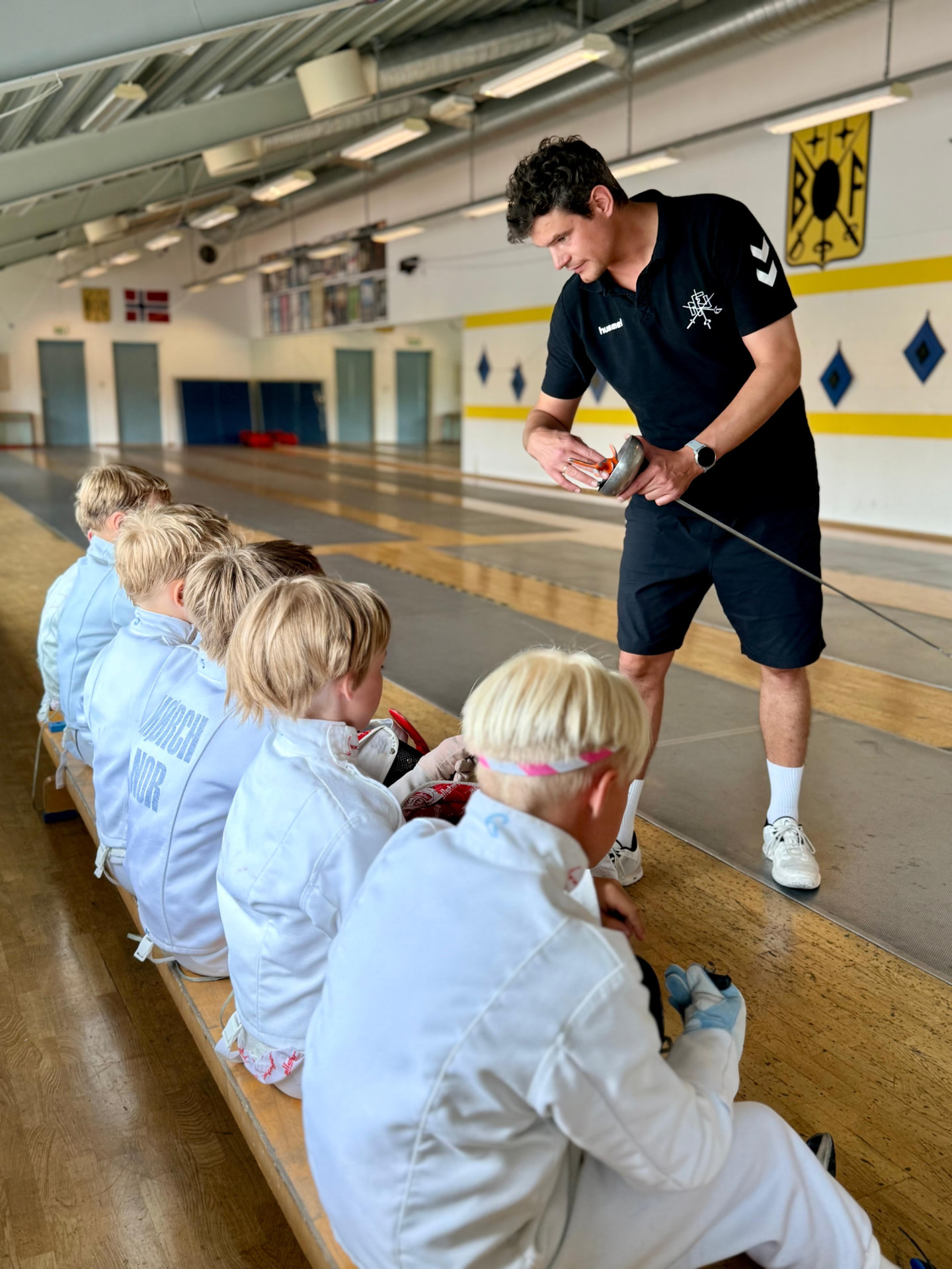 Trener viser fekteteknikk til barn i Bygdø Fekteklubb
